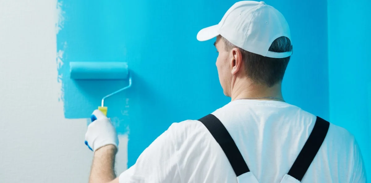 Painter applying blue paint with a roller